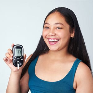 smiling girl holding her blood sugar monitor